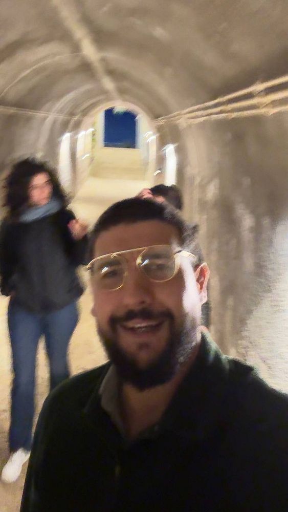 A group of friends is captured in a dimly lit tunnel, with one person smiling in the foreground.