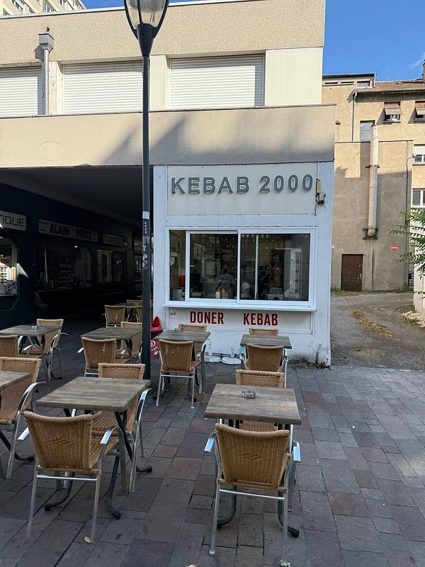A kebab shop named 'Kebab 2000' with outdoor seating is depicted in the image.