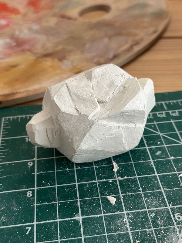 A sculpted, planar representation of a lemon is placed on a cutting mat.