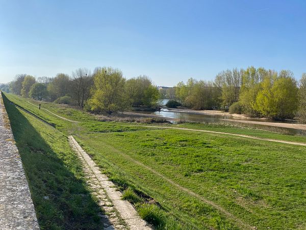 A person runs along a pier at sunrise or sunset with a modern city skyline backdrop.