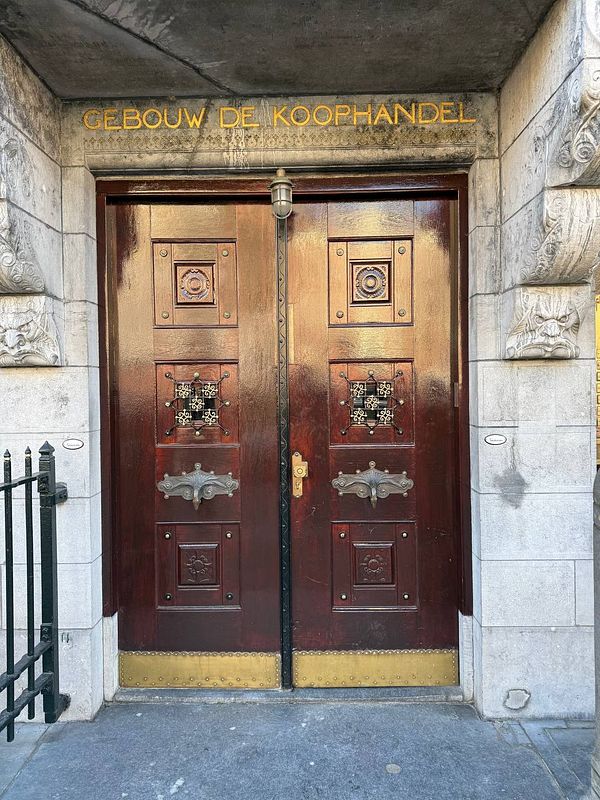The image features an ornate entrance with double wooden doors and decorative elements.