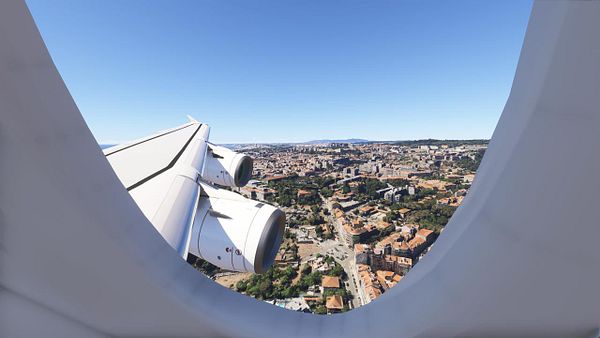A view from an airplane window showcasing the wing and engine of an A380 flying over Lisbon.