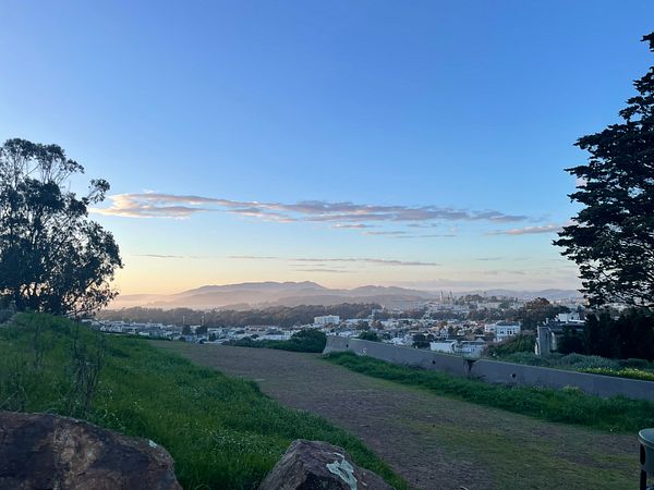 A scenic view of San Francisco at sunset, showcasing the city skyline and surrounding hills.