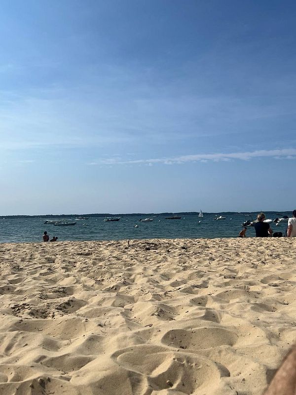 A serene beach scene in France with soft sand and a clear blue sky.