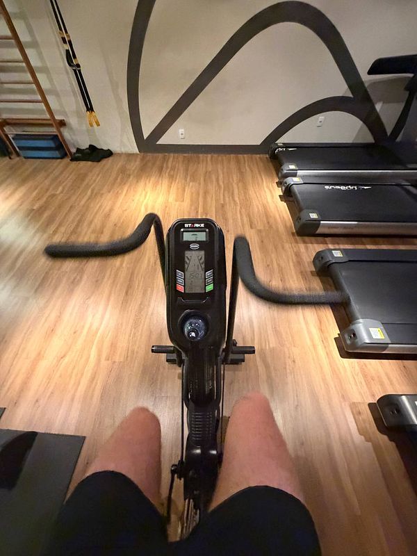 A woman in a cute gym outfit is sitting on a wooden bench outdoors surrounded by a natural garden setting.