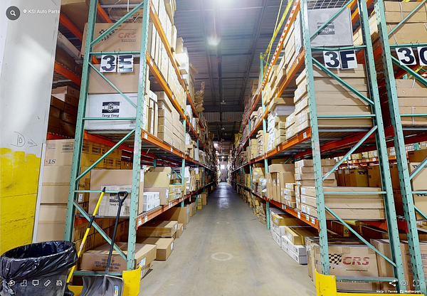 A wide aisle in a warehouse filled with stacked boxes on metal shelving units.
