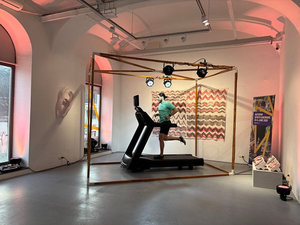 A runner on a treadmill is showcased in a gallery setting as part of a promotional event for an upcoming race.
