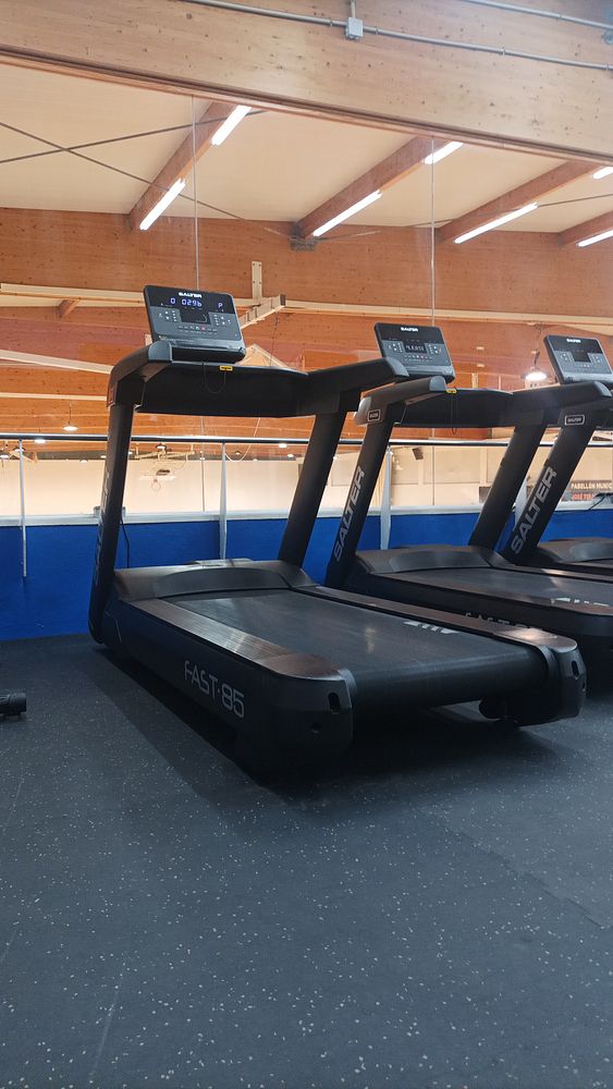 The image features a row of treadmills in a gym setting.