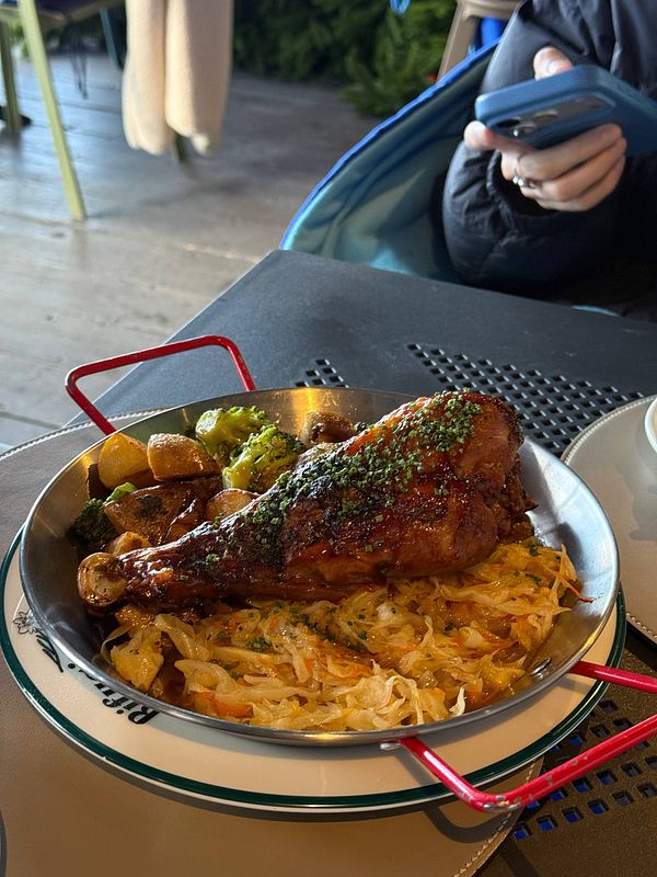 A delicious meal featuring roasted chicken leg, vegetables, and potatoes served in a stylish dish.