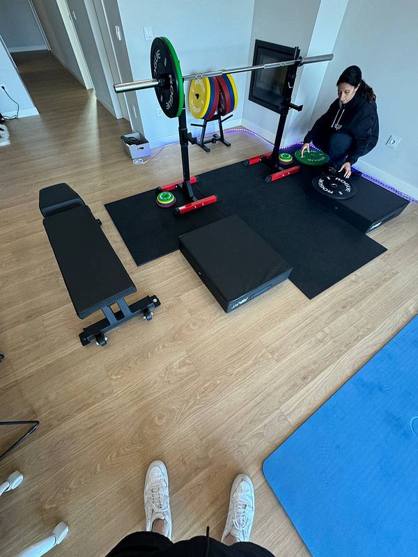 A home gym setup featuring weightlifting equipment and a person organizing weights.