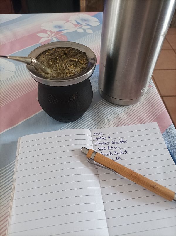 A cozy workspace featuring a traditional mate setup alongside a notebook and pen.