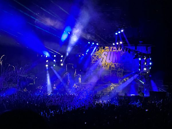 A vibrant scene from the final Sum 41 concert featuring a lively crowd and dramatic stage lighting.