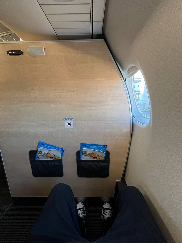 The image captures a view from a business class seat on an airplane, showcasing the legroom and nearby amenities.
