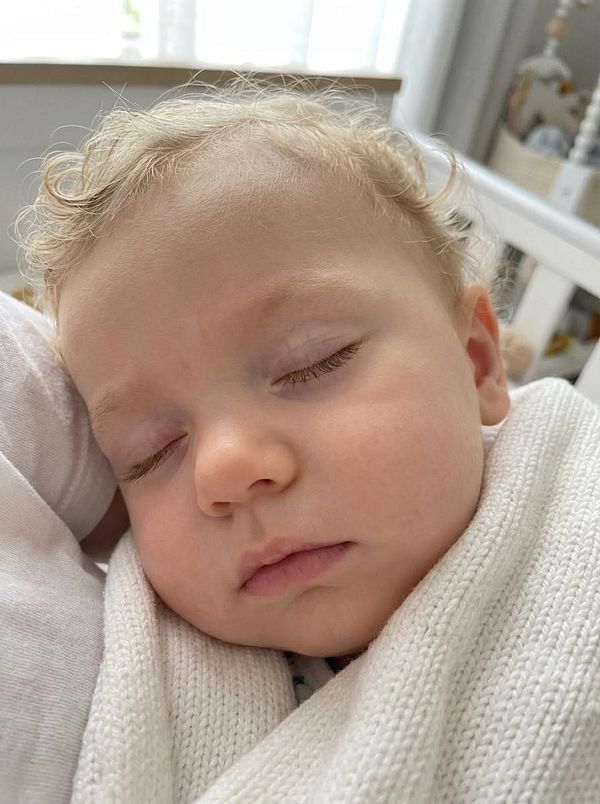 Portrait of a smiling woman with two artificial baby faces floating beside her head.