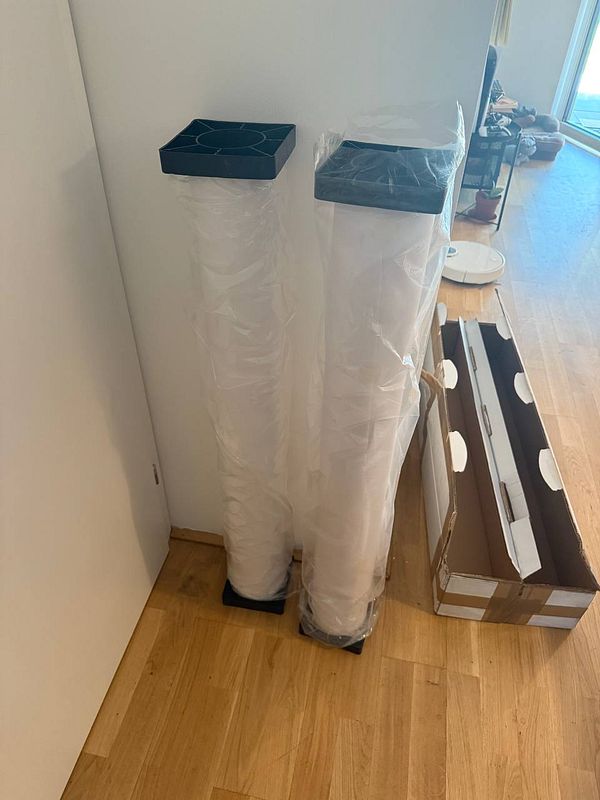 Two rolls of industrial-grade laminate foil are standing upright next to a cardboard box.