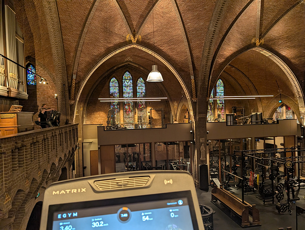 A unique gym setup inside a church featuring workout equipment and stained glass windows.