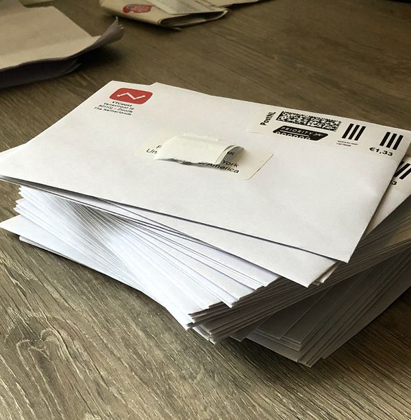 A stack of envelopes is neatly arranged on a wooden surface.