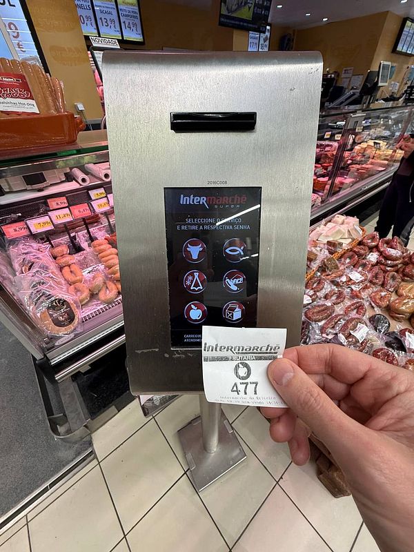 A person is holding a ticket from an automated service kiosk at a supermarket in Portugal, specifically for weighing produce.