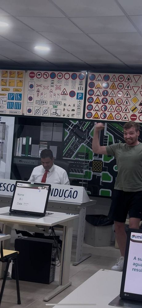 A man celebrates in a driving theory test center while another person sits at a desk.