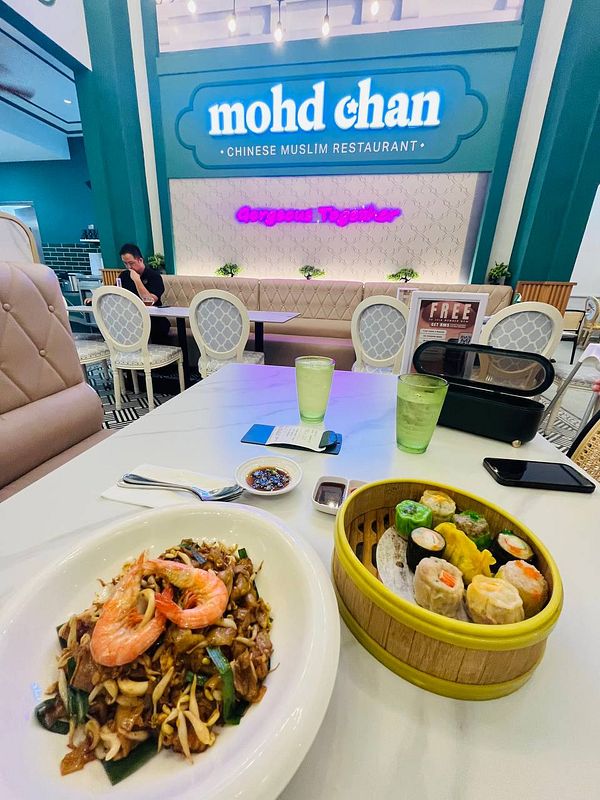 A dining table at a restaurant featuring a variety of dim sum and a noodle dish.