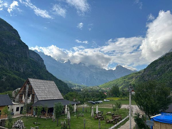 A scenic view of a mountainous landscape with a rustic building and outdoor seating area in the foreground.