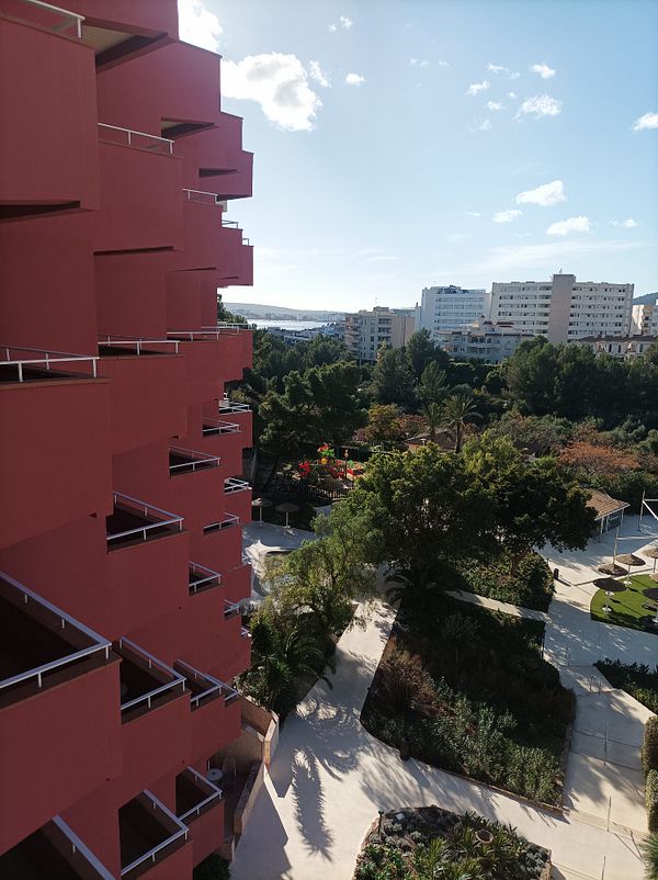 A view from a hotel balcony overlooking a landscaped area and distant buildings.