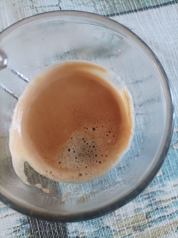 A close-up view of a glass containing a freshly brewed espresso.