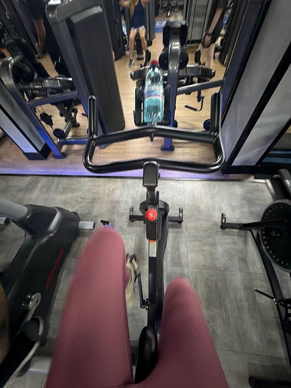 Photo of a muscular man working out in a gym holding a dumbbell in one hand.