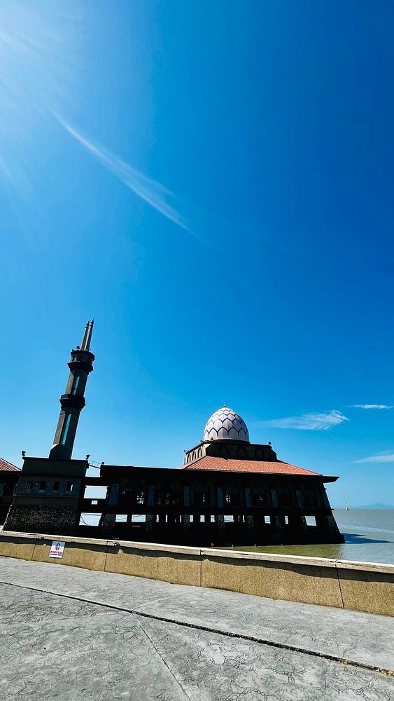 Photograph of a floating mosque at sunset with intricate architectural details and reflection in water.