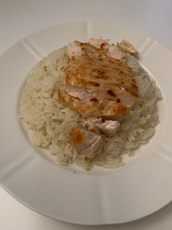 A plate of khao man gai featuring sliced grilled chicken over fragrant rice.