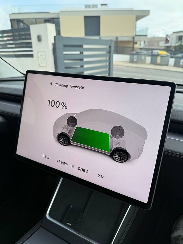 The image displays a car's charging interface showing a fully charged battery.