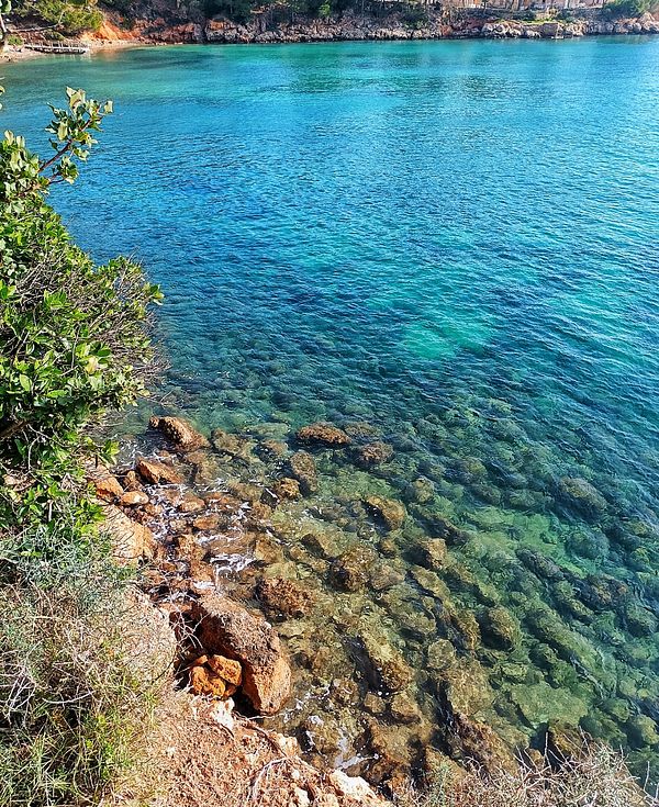 A serene coastal view featuring clear turquoise waters and rocky shorelines.