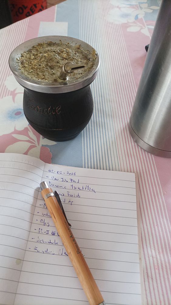A wood table with mates, a glass jug, cups, and a cigar, suggesting a social mate drinking setting.