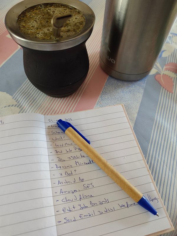 Photo of a dancing brown bear figurine placed on a colorful, cluttered desk with stationery and a laptop keyboard.