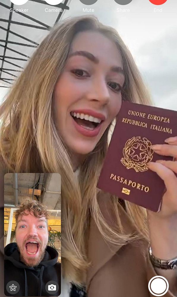 A woman joyfully holds her Italian passport while video chatting with a man who is also smiling.
