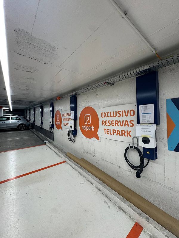 A row of electric vehicle chargers marked as 'out of service' in a parking garage.