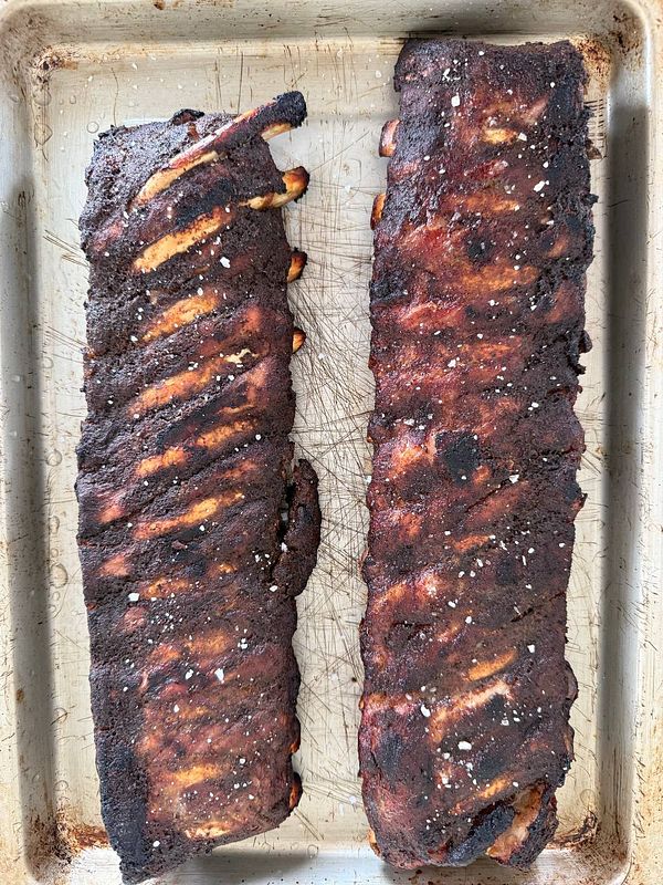 Two slow-cooked ribs are displayed on a baking tray.