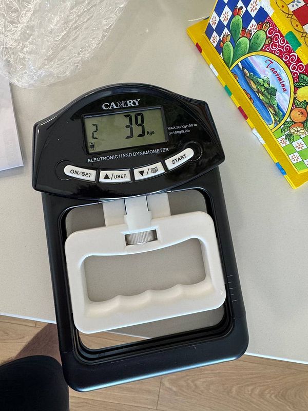 An electronic hand dynamometer displaying grip strength measurements.
