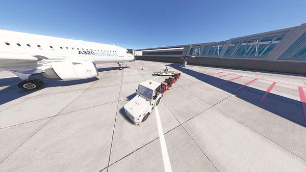 An Airbus A320 is parked at an airport with a baggage tug positioned nearby.