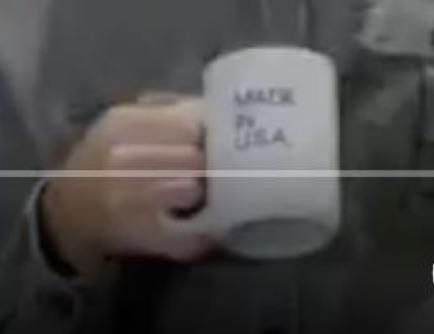 A person is holding a white mug with the text 'MADE IN USA' written on it.