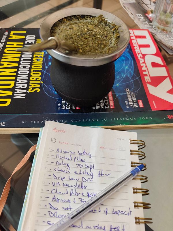 Photo of a table with a mate gourd and straw, surrounded by stationery and a laptop keyboard, symbolizing a casual Monday working environment.