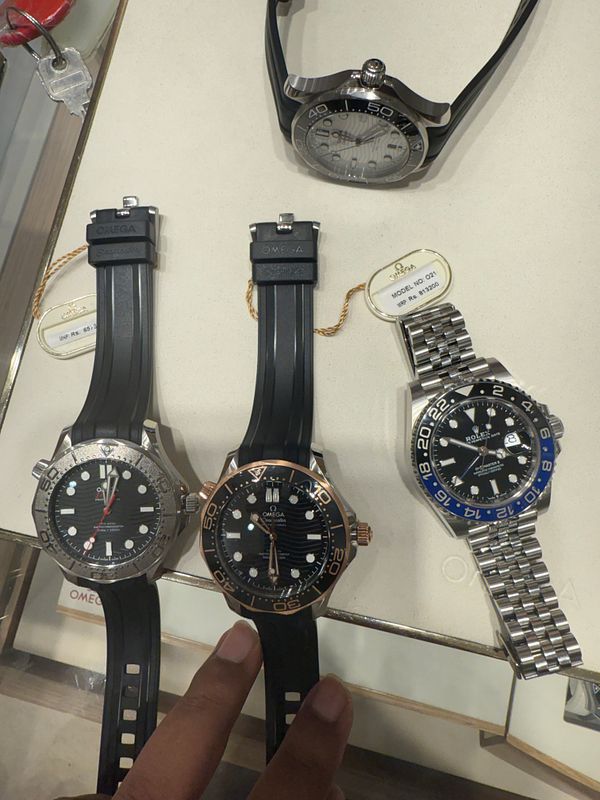 The image features several Omega watches displayed on a counter.