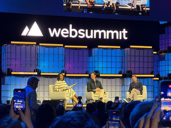 A panel discussion at the Web Summit featuring three speakers on stage.