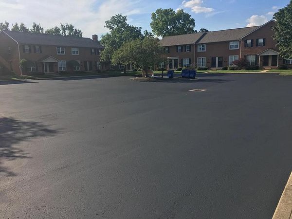 A freshly paved parking lot adjacent to residential buildings.