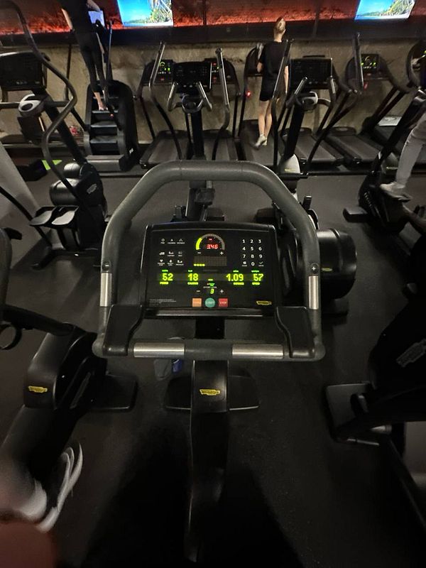 A close-up view of a gym exercise machine's control panel with various metrics displayed.