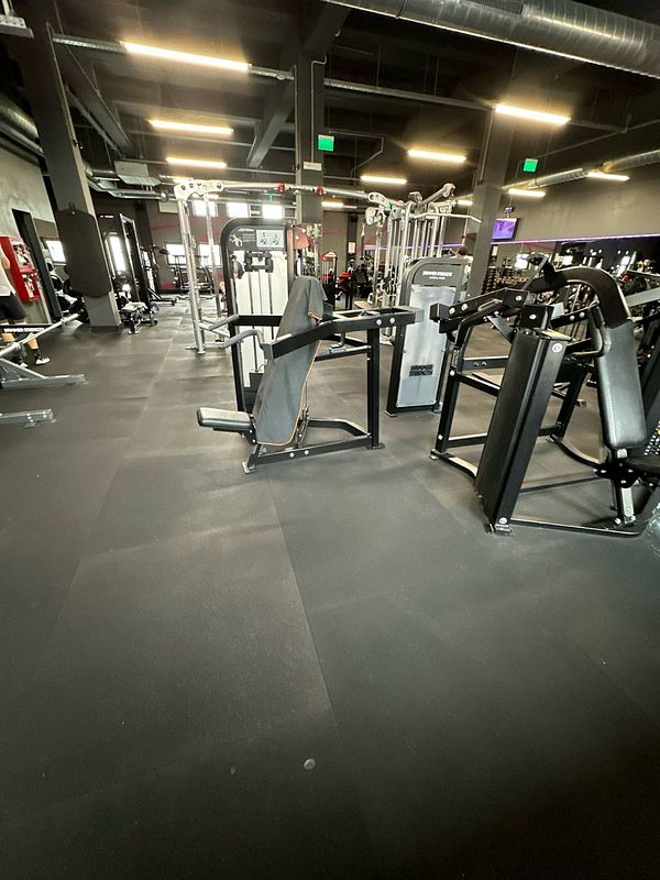 A modern gym interior featuring various exercise machines and equipment.