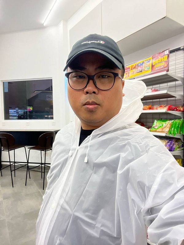 A person wearing a clear poncho stands inside a convenience store.