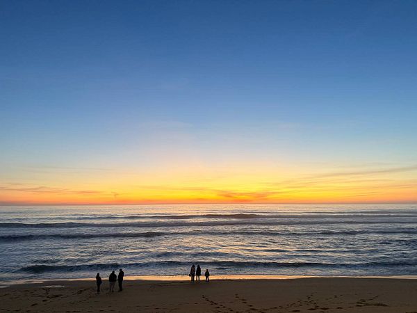 A lively beach scene with people engaging in water activities under a cloudy sky.