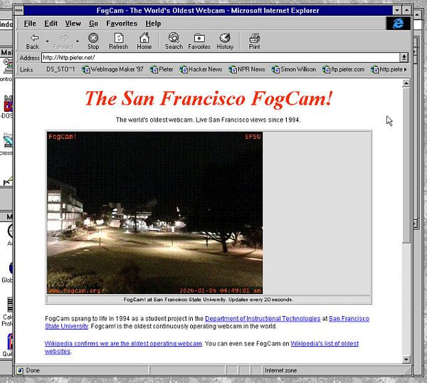 A foggy daytime image showing a residential area with utility poles and houses along a road, enveloped in thick mist.
