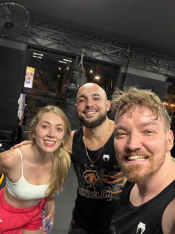 A young man dressed for a Muay Thai workout is standing in a boxing ring, ready for training or competition.
